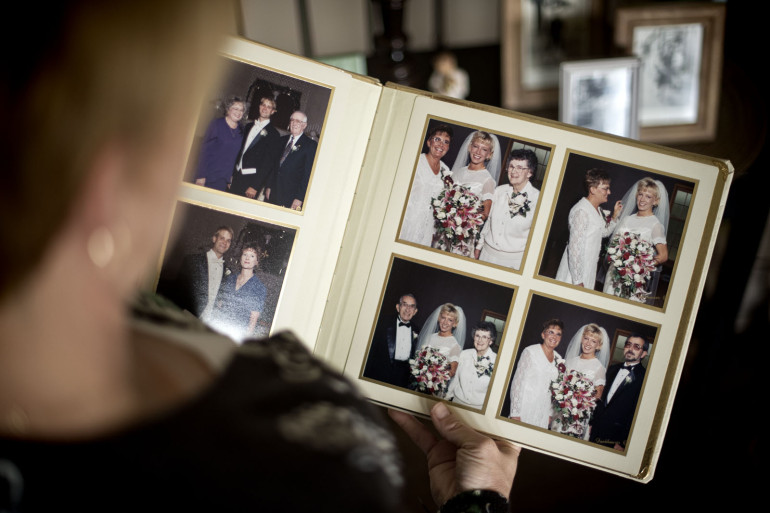 Kristin Sigg looks at wedding photos that include her mother. (Travis Young/Austin Walsh Studio for KHN)