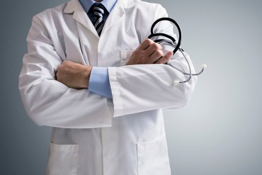 Doctor holding a stethoscope with arms crossed and copy space