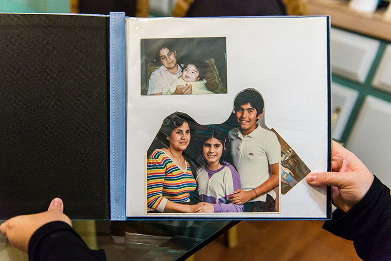Navarro looks through old childhood photographs to find a picture of her mother, Rosa Maria, who also had the familial Alzheimer’s. (Heidi de Marco/California Healthline)