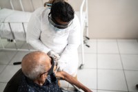 A health worker vaccinates a senior man
