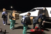 a team of five people carry boxes of vaccines