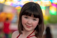 young girl with brown, shoulder length hair and red strappy top