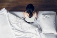 Woman sitting on edge of bed waking up