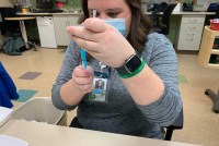 Beth Ann Wilmore checks a vaccine vial at her community health center