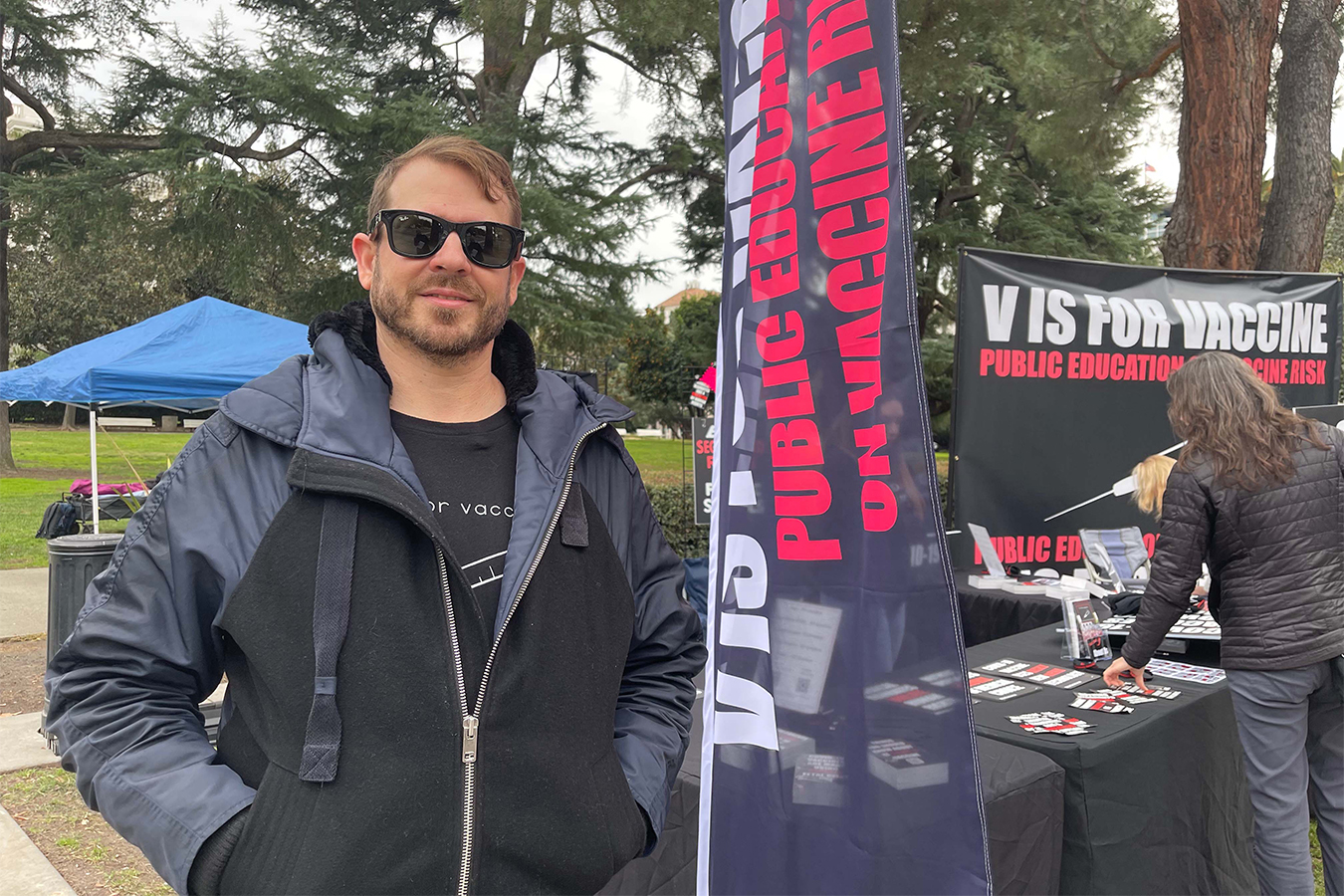 Joshua Coleman, co-founder of the group V Is for Vaccine, stands next to a booth set up at an anti-vaccine rally at the California Capitol in early January.