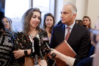 A group of reporters hold microphones to RaDonda Vaught, who is standing to the left of her lawyer, Peter Strianse.