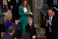 13-year-old Joshua Davis stands up as people around him applaud and smile during the State of the Union address.