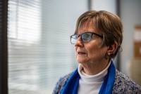 Lise Hamlin looks to the left in front of an office window. A hearing aid is visible in her ear.