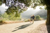 An elderly couple walk on a trail holding hands.