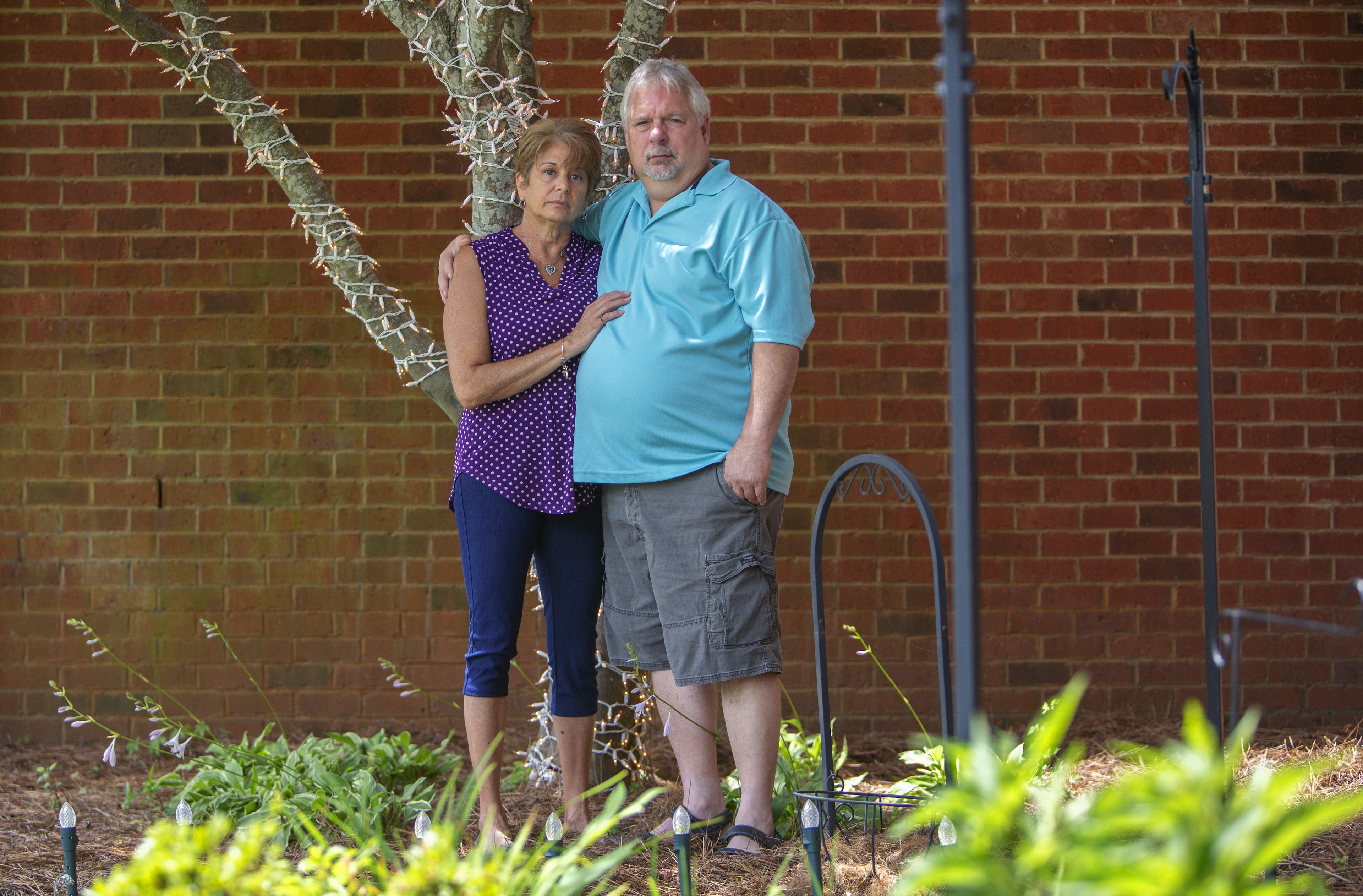 a couple stand beside a tree they light in honor for their son who died of an overdose