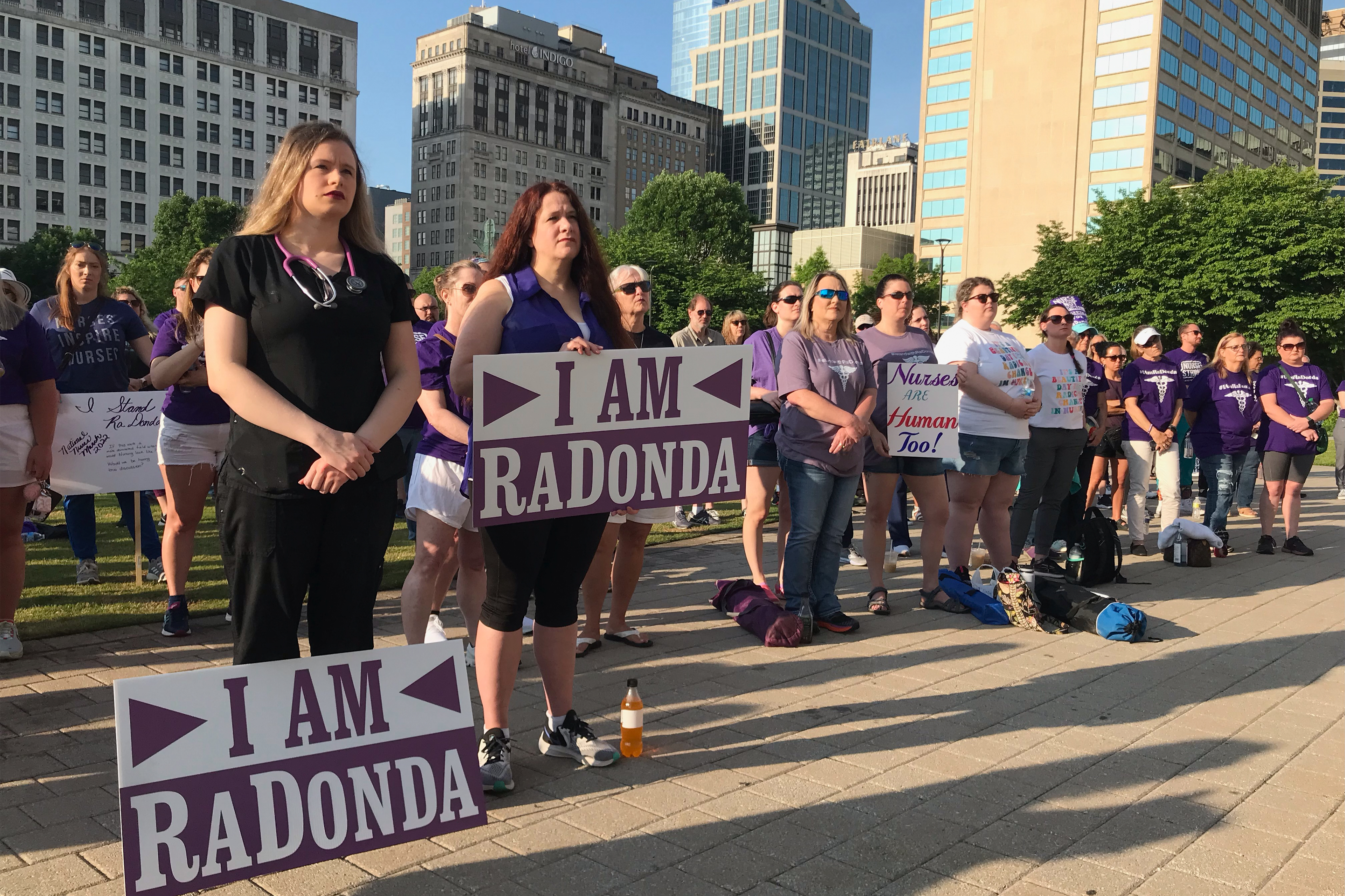 A crowd of demonstrators is seen holding signs that read, "I am RaDonda." Most of the crowd is wearing purple.