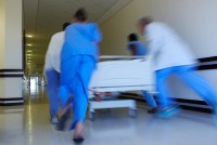 A photo shows nurses and doctors rushing a bed down a hospital corridor. They are blurred by their motion.