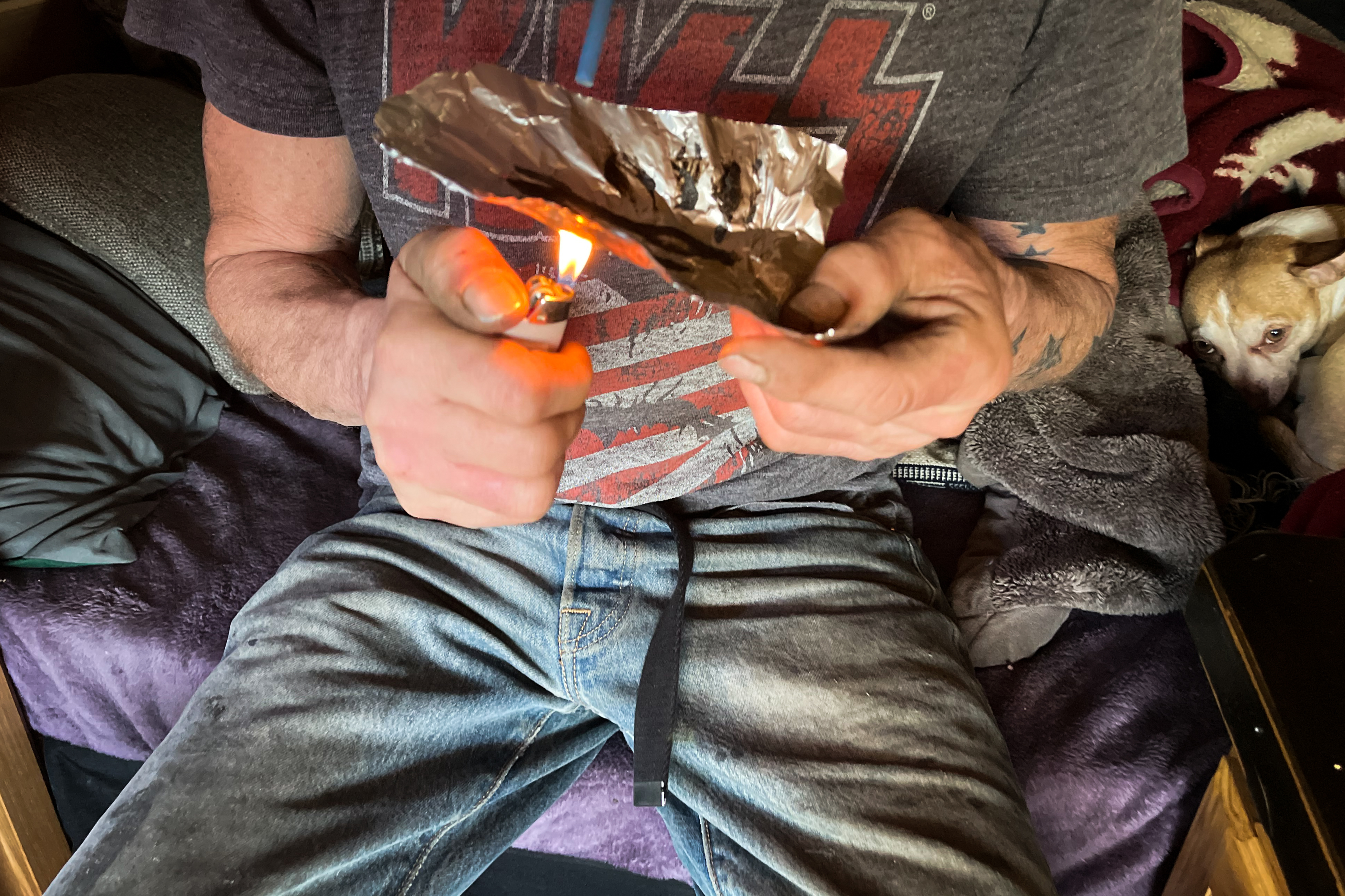 A closeup photo shows a person preparing to smoke heroin on foil. person