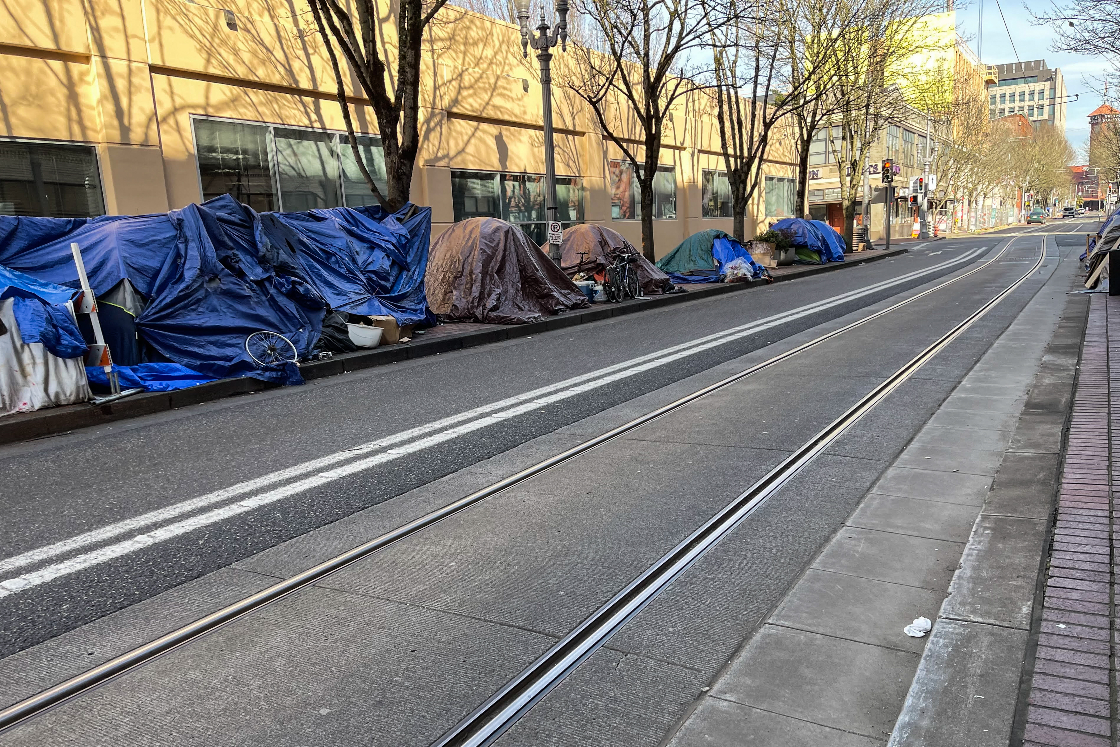 A photo shows a row of tents lining the street in downtown Portland, Oregon.