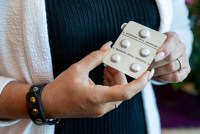 A close up photo shows a woman holding a sealed packet of abortion pills.