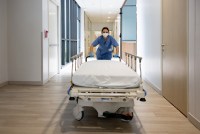 A nurse pushes a gurney down a hallway inside of a hospital.