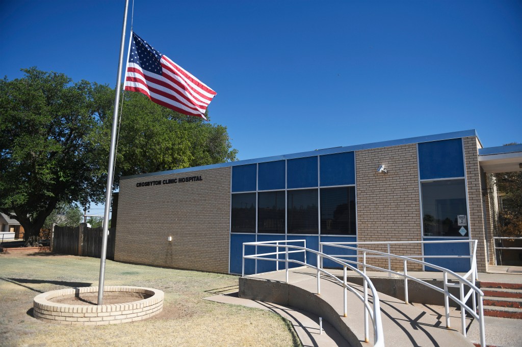 A photo shows the exterior of Crosbyton Clinic Hospital. An American flag is seen on a pole to the left of the entrance.