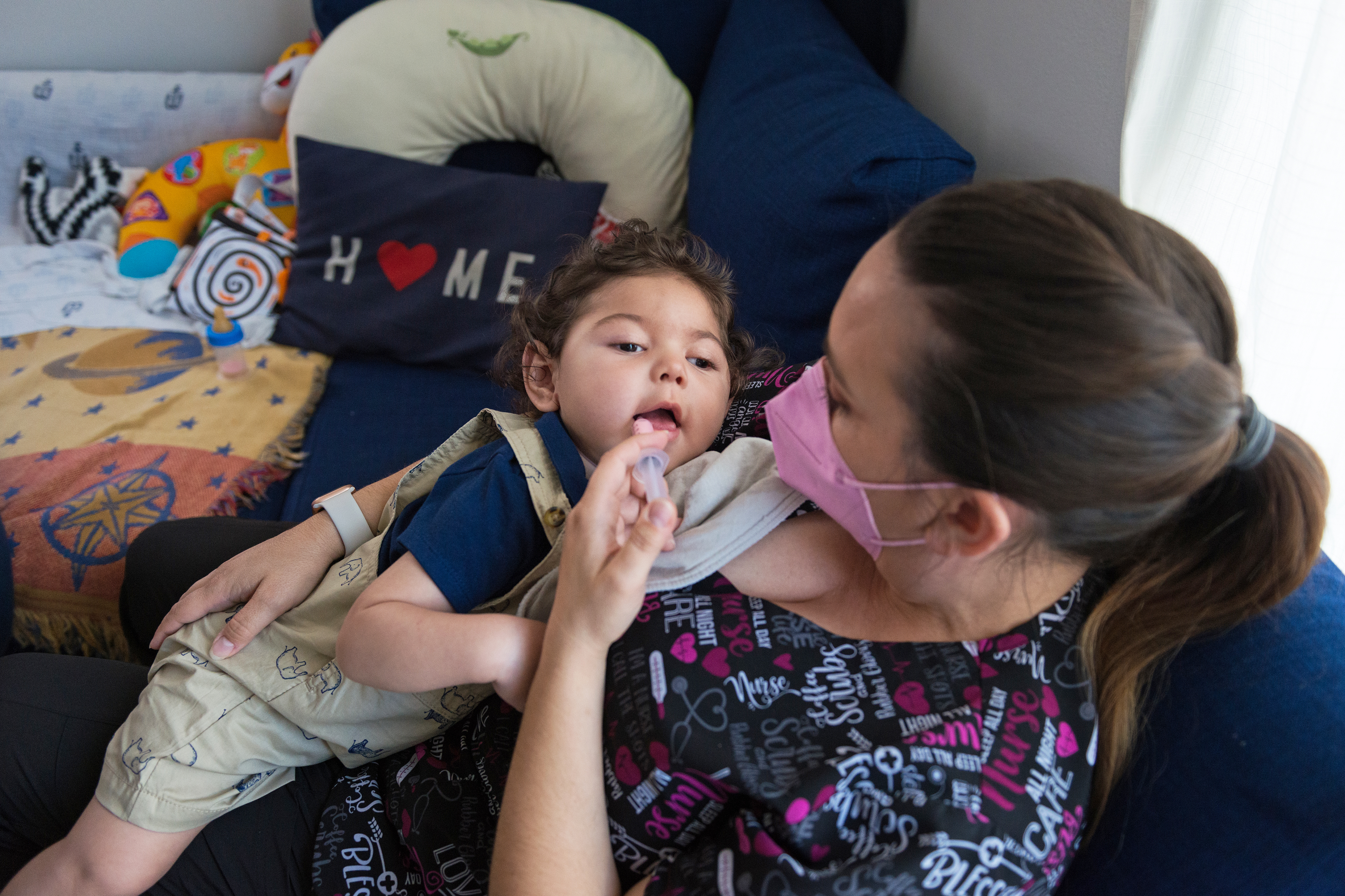 A photo shows a nurse giving 17-month-old Aaron Martinez medicine via an oral syringe.