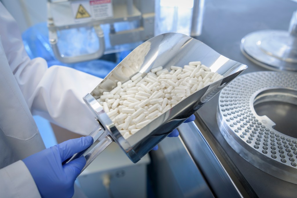 A photo shows a pharmaceutical manufacturer filling capsules with medicine.