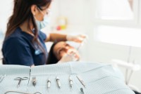 dentist working on a patients mouth with dentistry tools laid out in the foreground