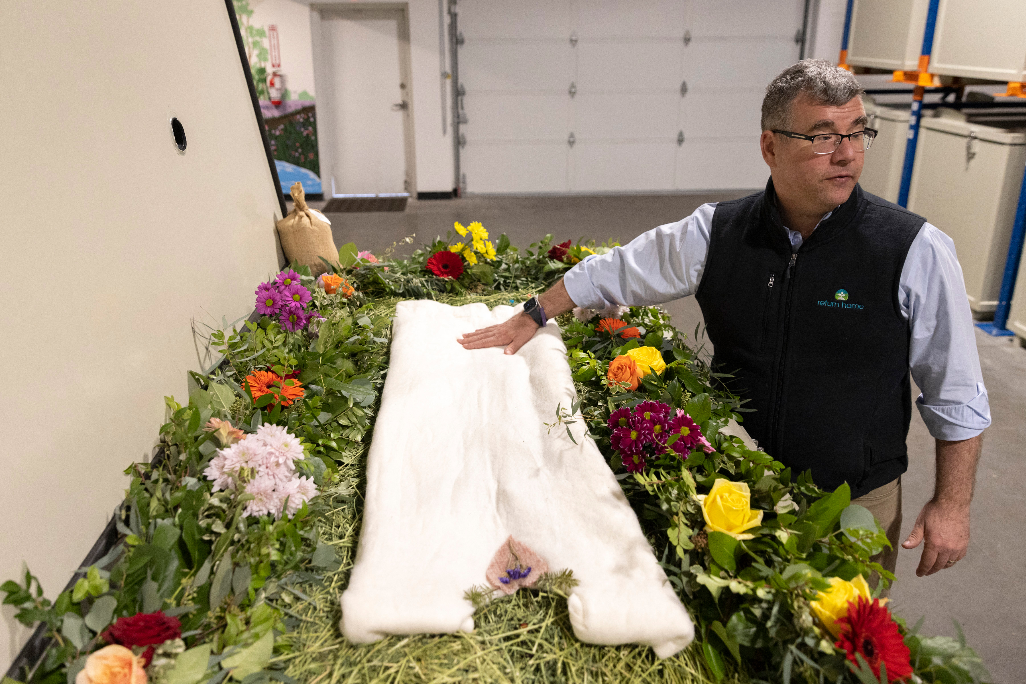 Op een foto staat Micah Truman naast een vat versierd met bloemen en composteerbare aandenkens bovenop een bed van stro.
