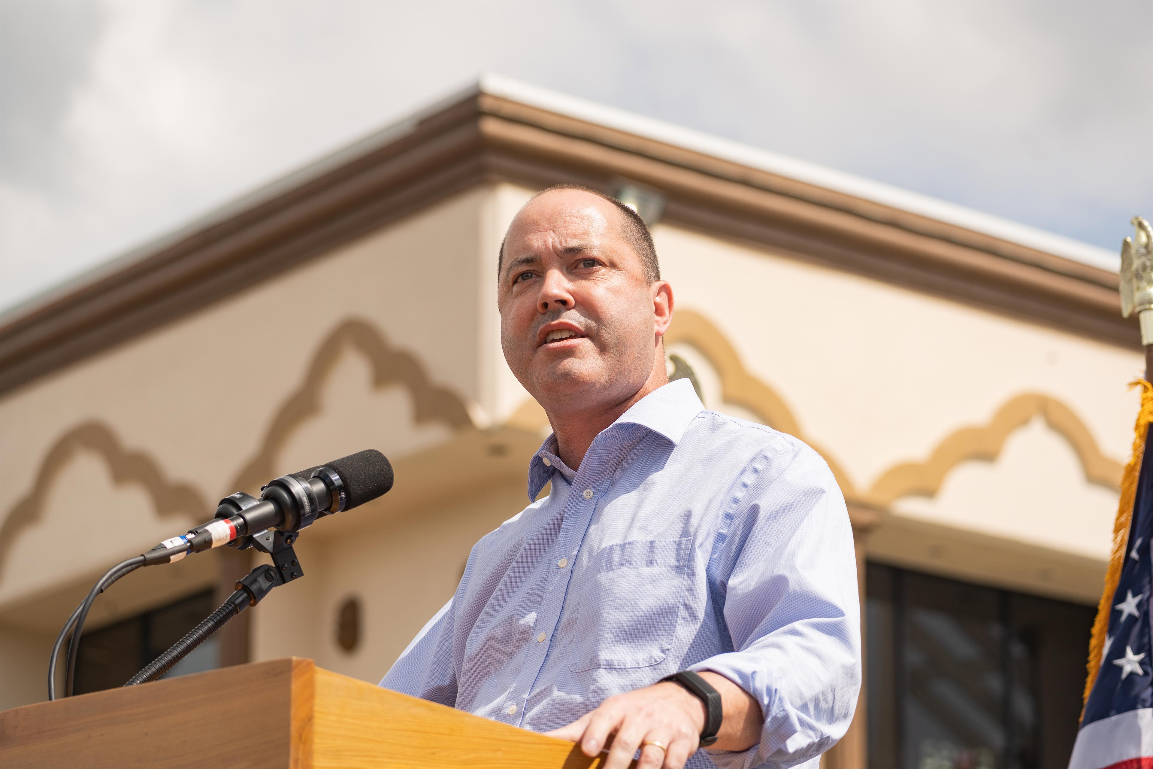A photo shows Chris Carr speaking into a microphone at a podium outside.