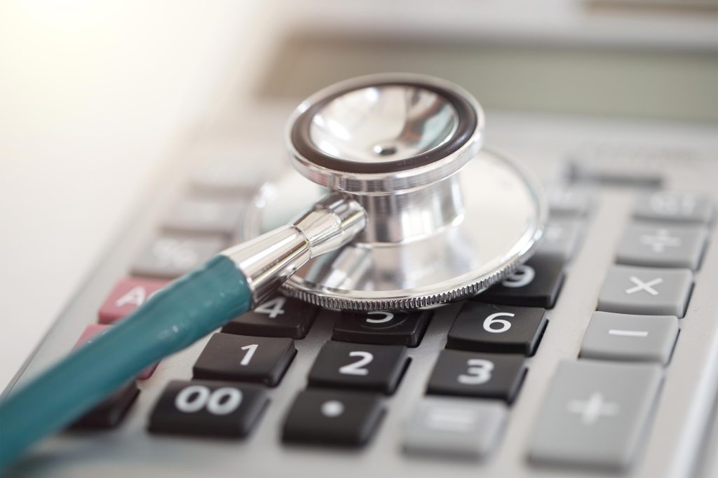 A photo shows a doctor's stethoscope on top of a calculator.