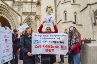 A photo shows two demonstrators holding a banner that reads, "Stop the corporate takeover of NHS GP surgeries. Get Centene out."