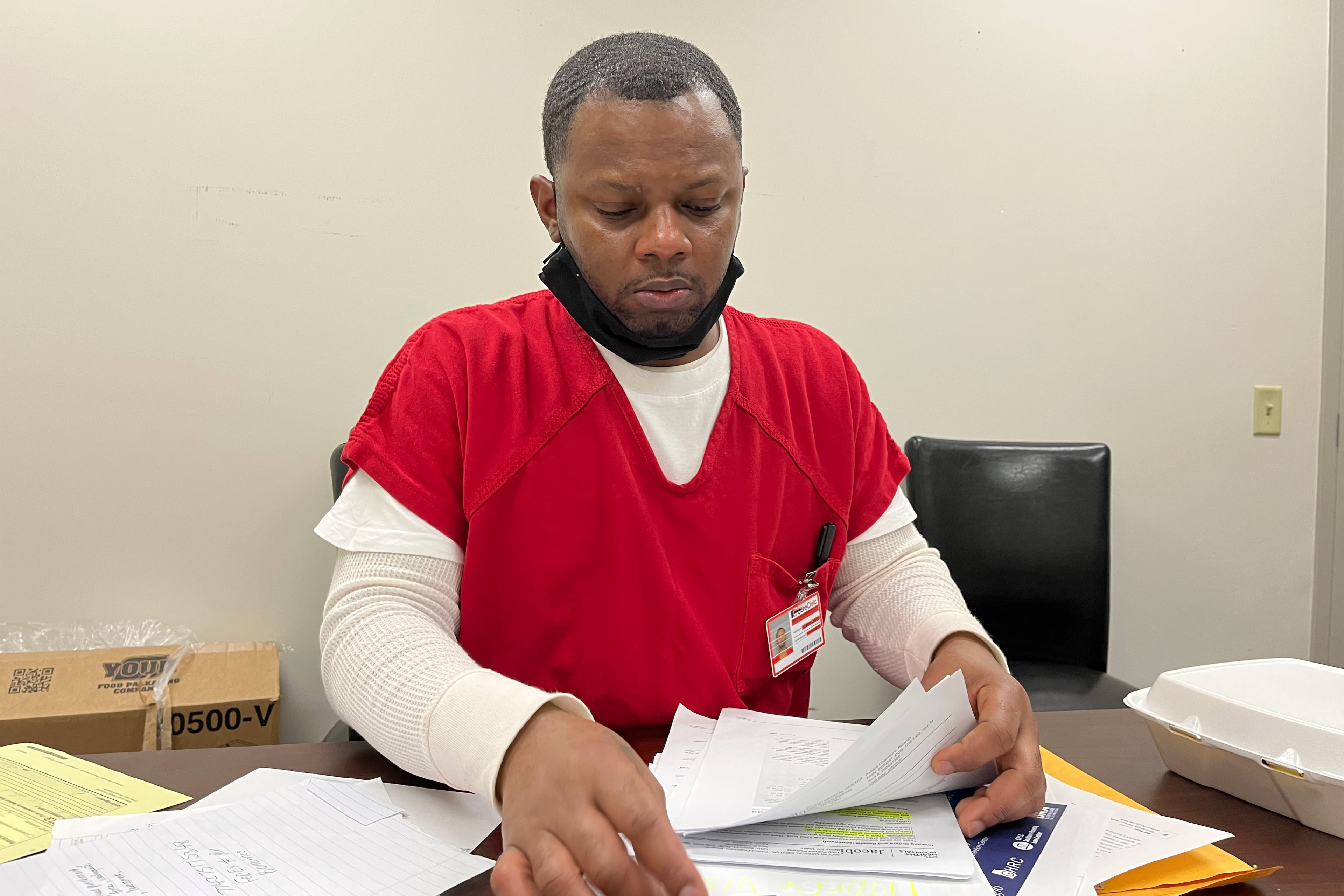 A photo shows Ricardo Chambers sitting at a desk, looking through papers.