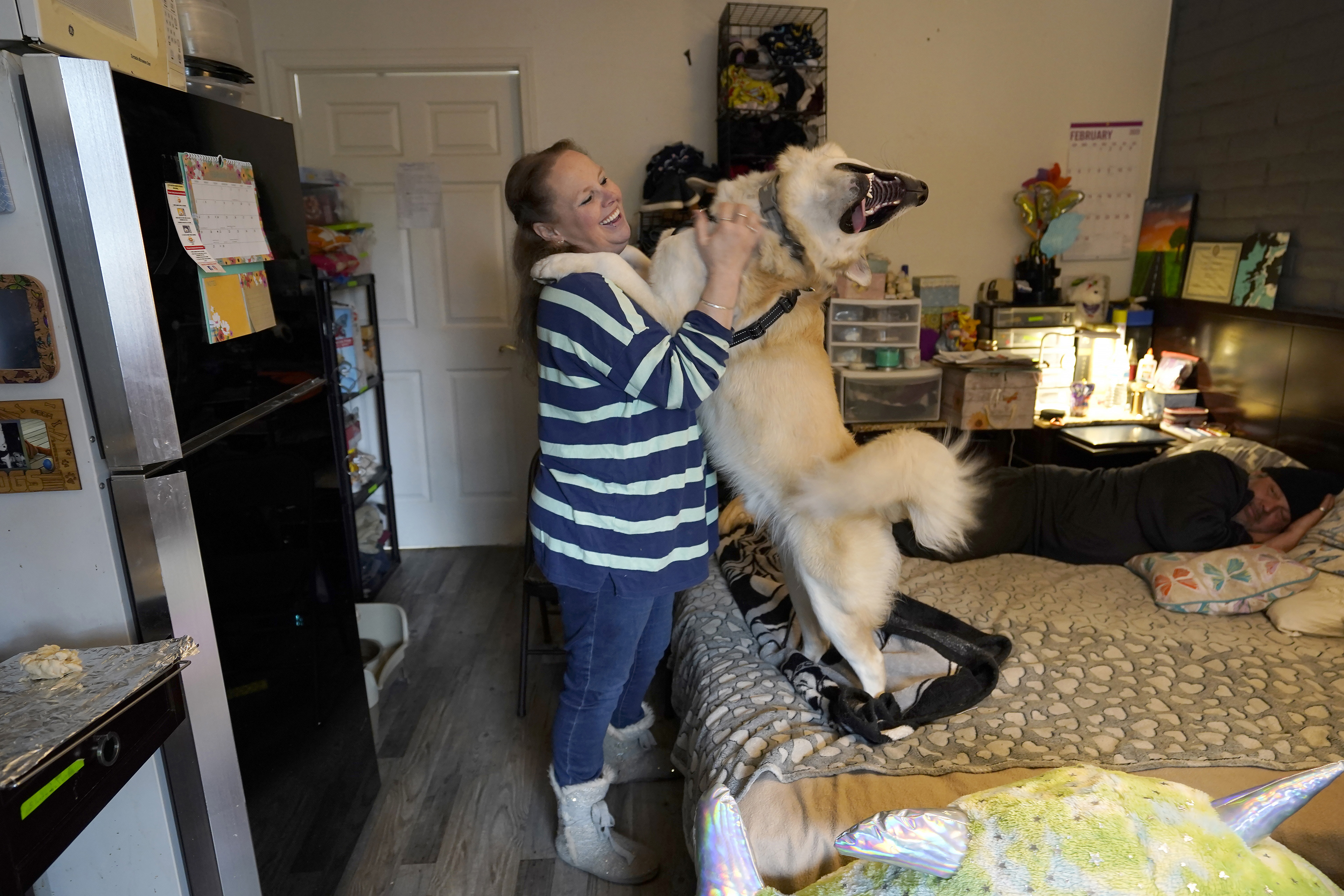 Stephanie Lammers pets her dog, who is standing on its hind legs with its front paws on her shoulders, visibly jubilant from the affection.