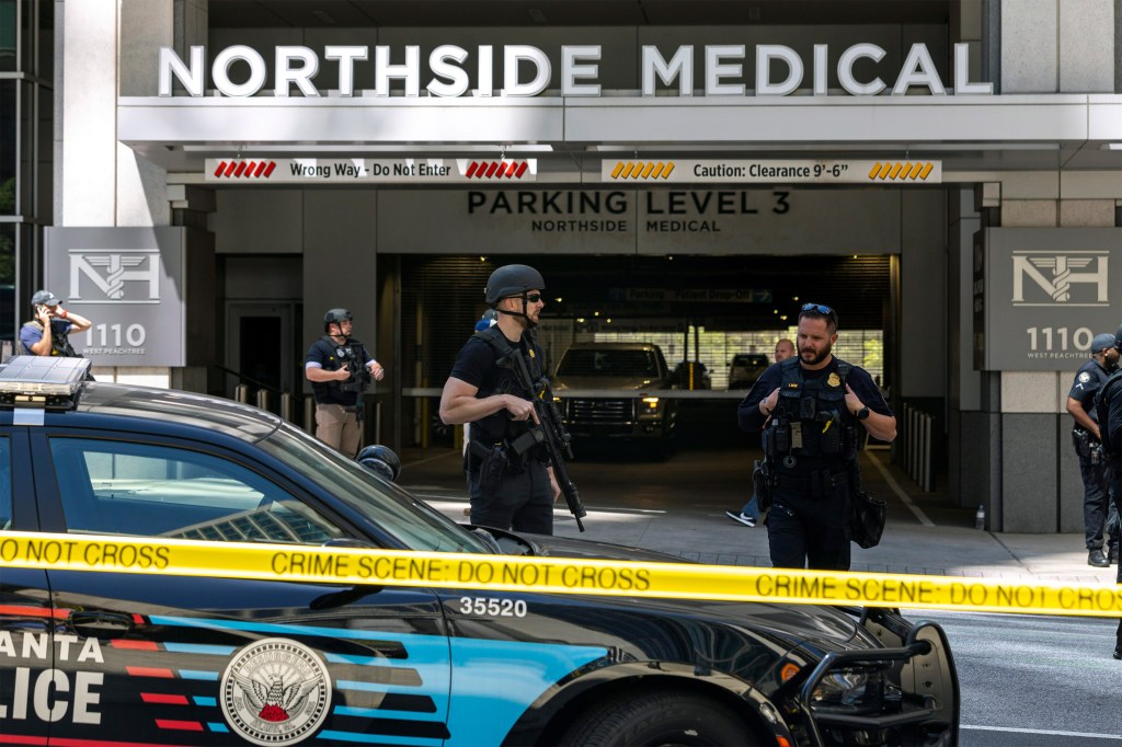A photo of police officers standing behind crime scene tape at the Northside Medical Midtown medical office.