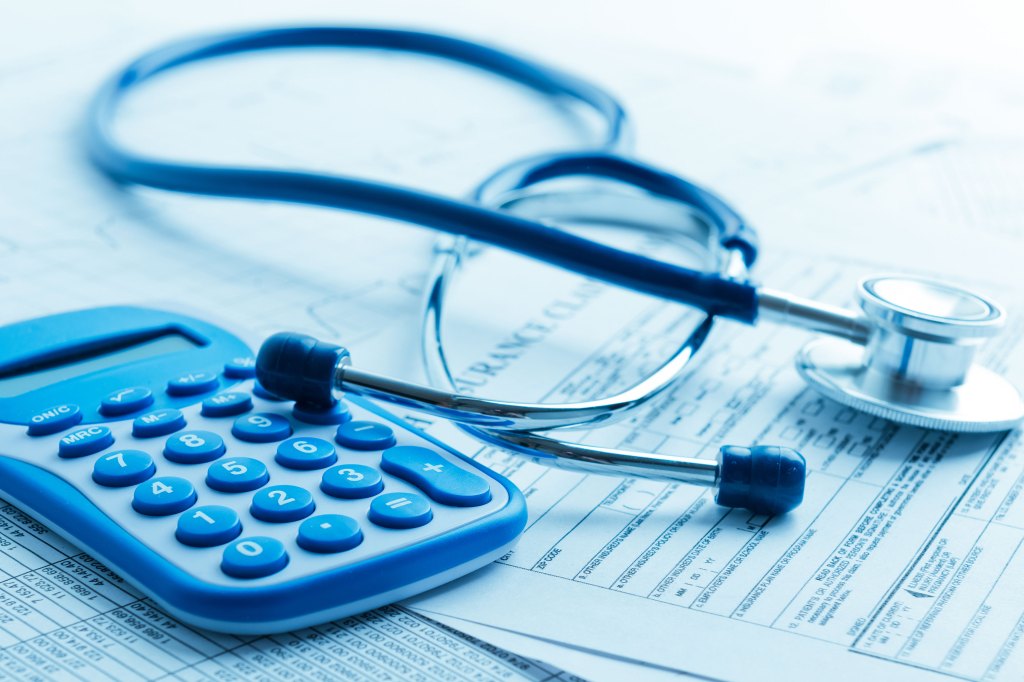 A photo of a stethoscope and calculator resting on top of paperwork.
