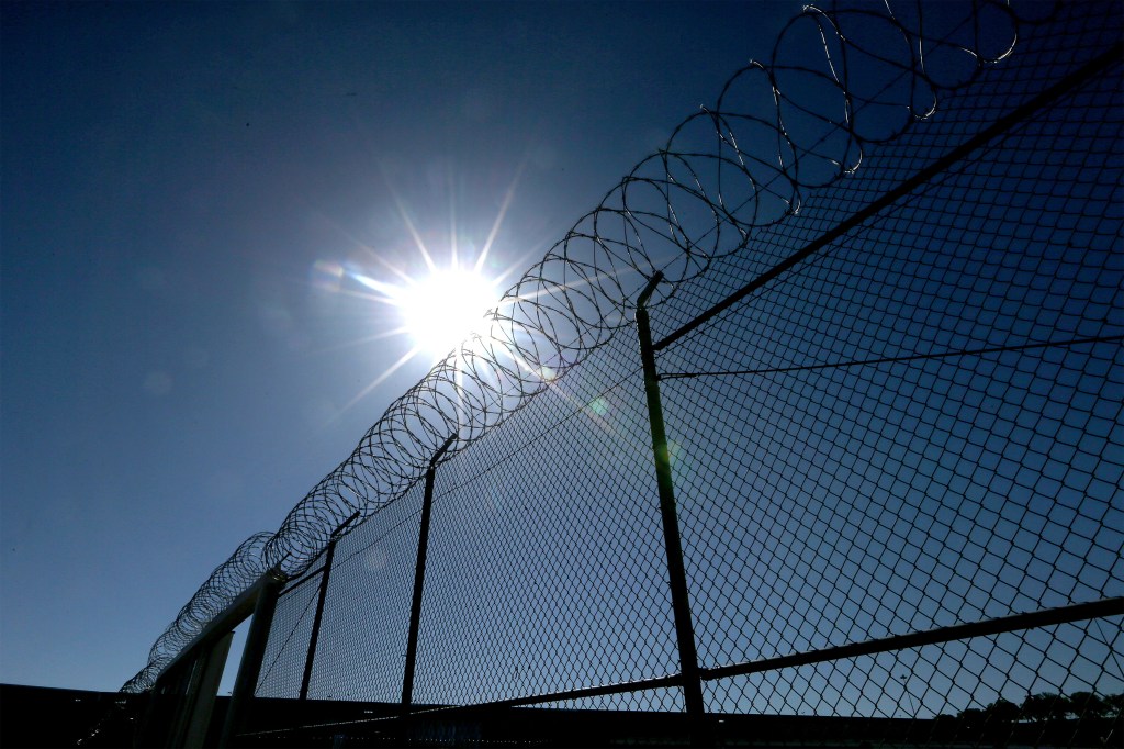 A photo of a fence with razor wire lining the top of it.
