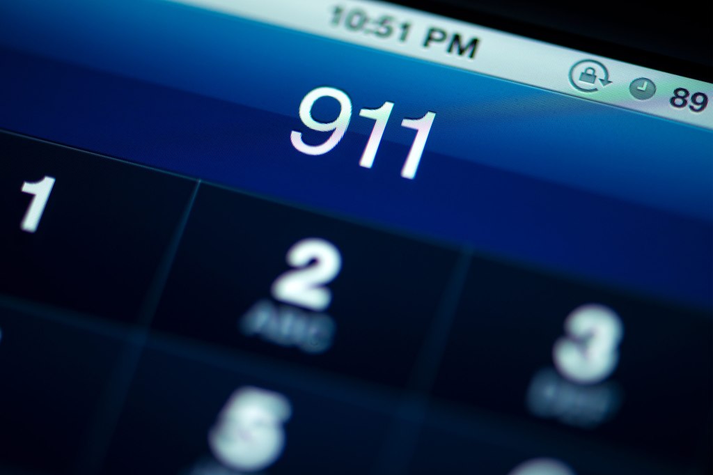 A photo of someone dialing 911 on a smartphone.