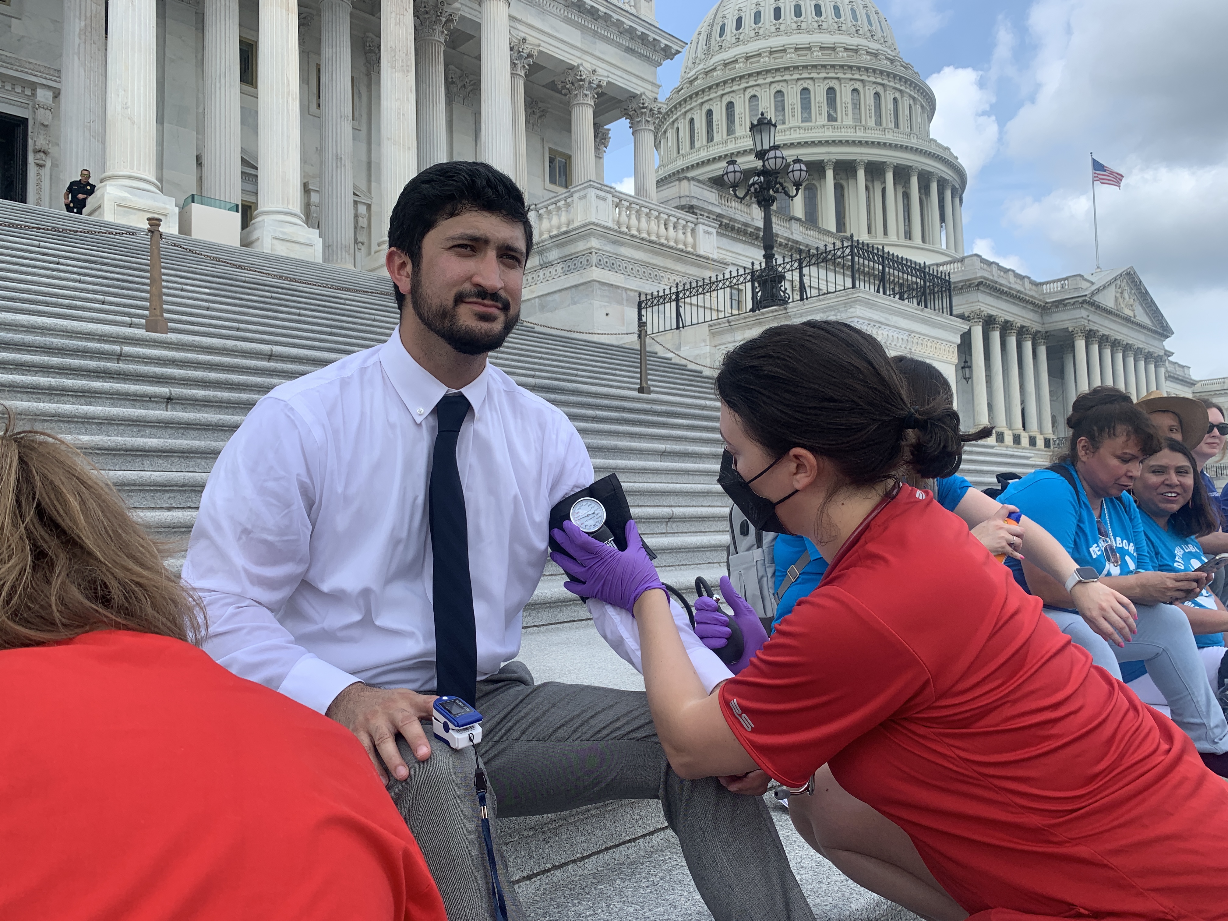 A registered nurse monitors on Rep. Greg Casar's heath while he sits on the steps of the U.S. Capitol.