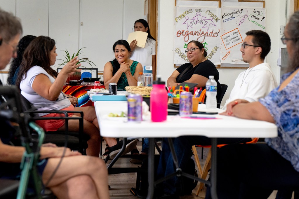 A photo of a community members sitting around a table at a meeting.