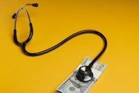 A photo of a stethoscope on top of a one hundred dollar bill.