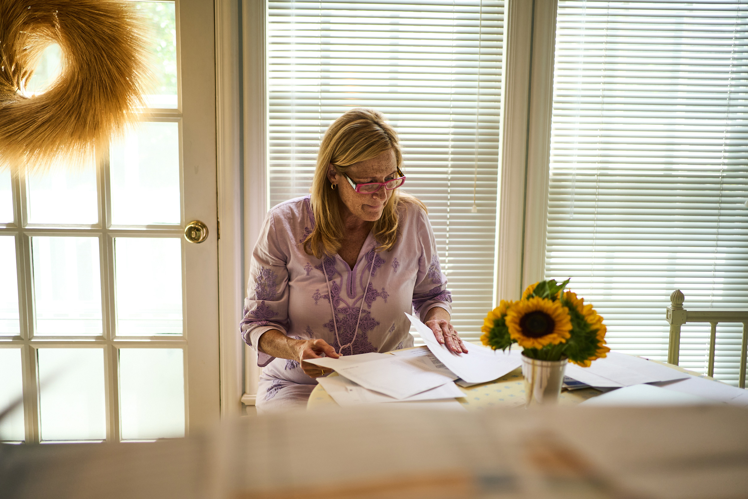 A photo of a woman looking over paperwork while sitting at a table.