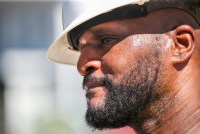 A photo of a man's face partially shaded by a hard hat in bright sunlight.