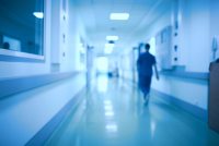 A photo of a person walking down a blurred hospital corridor.