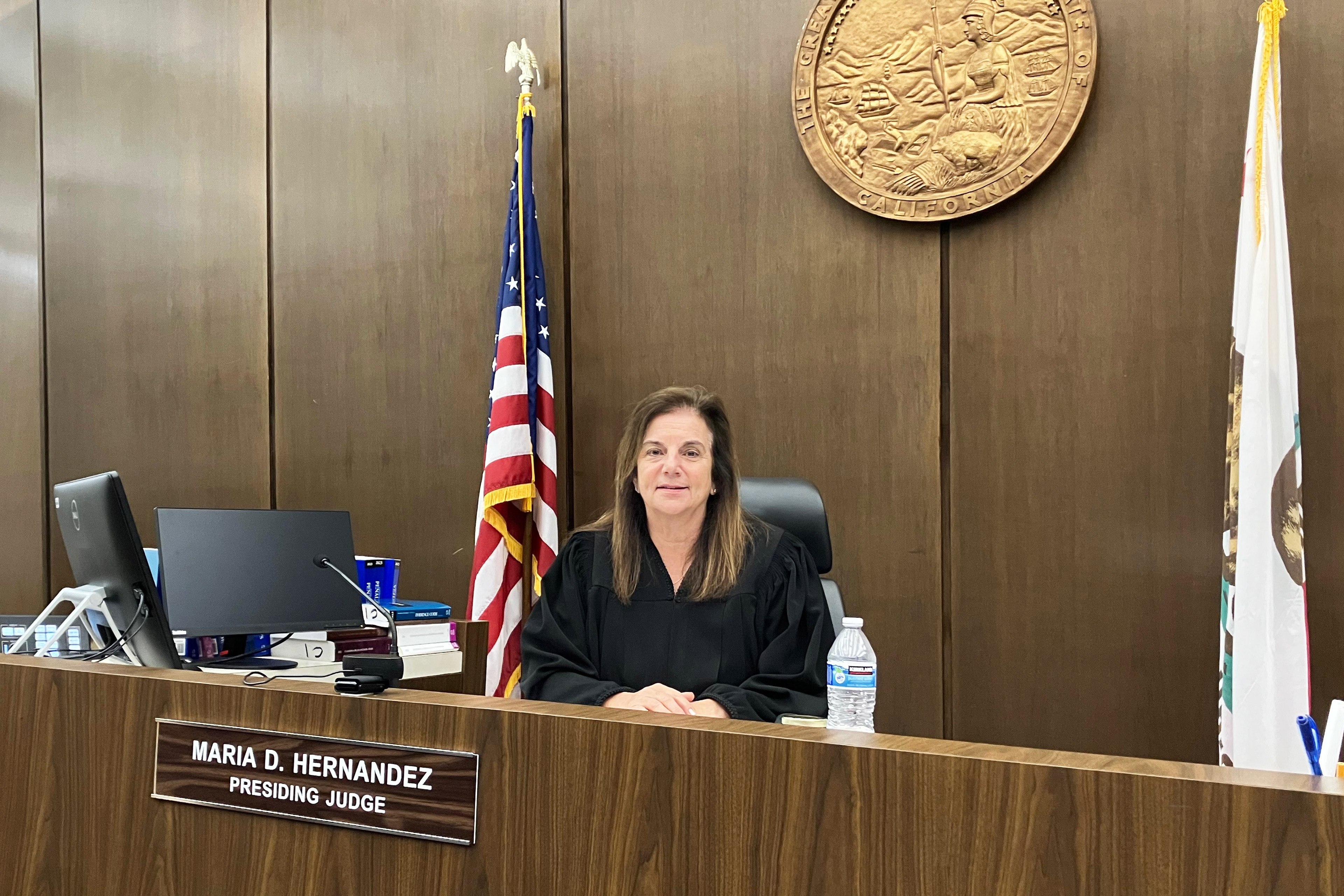 A photo of a judge sitting at their bench in a courtroom.