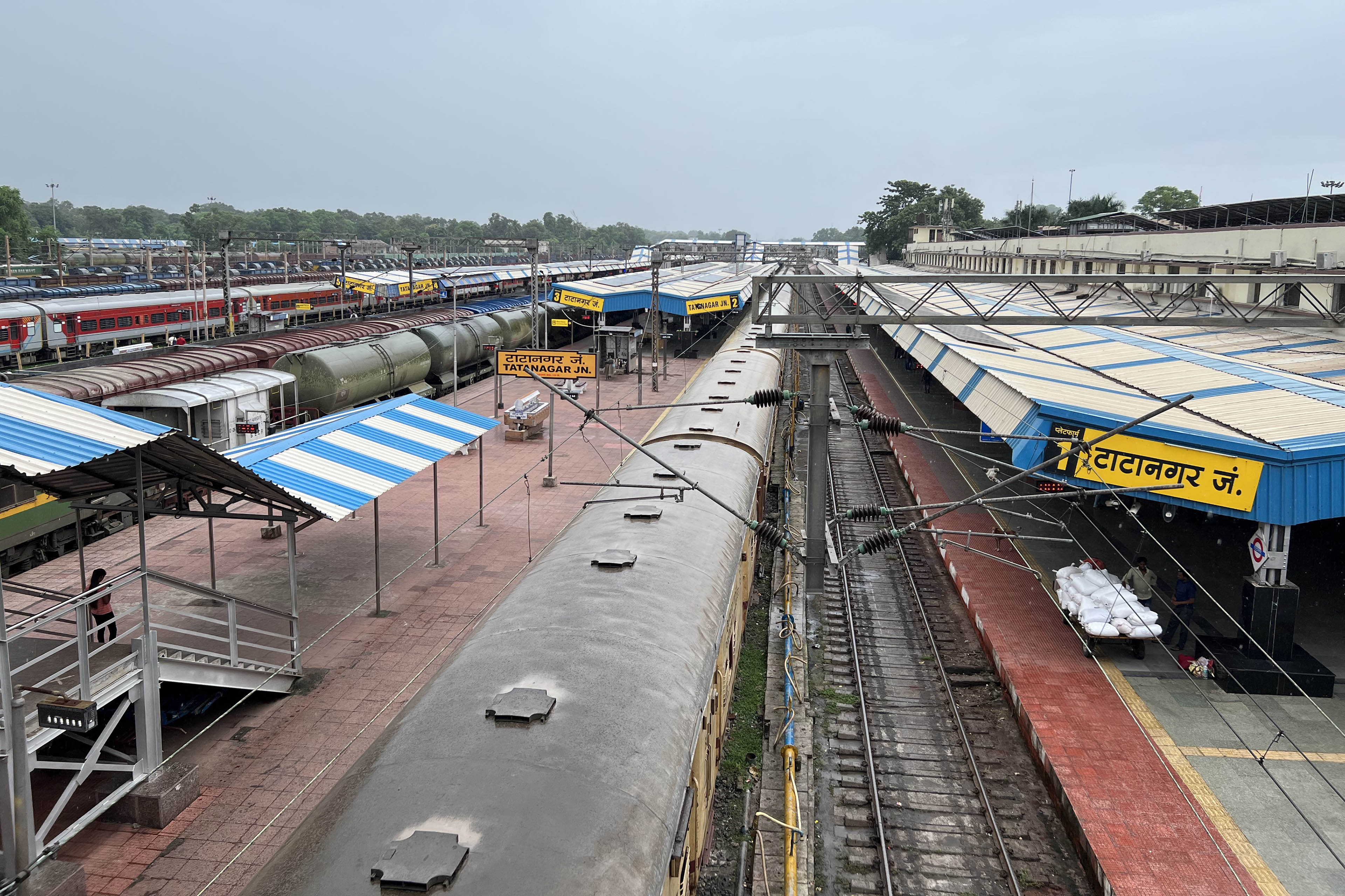 An aerial view of the Tatanagar Railway Station in 2022. A long track and bright blue-and-yellow platform stretch out into the distance.