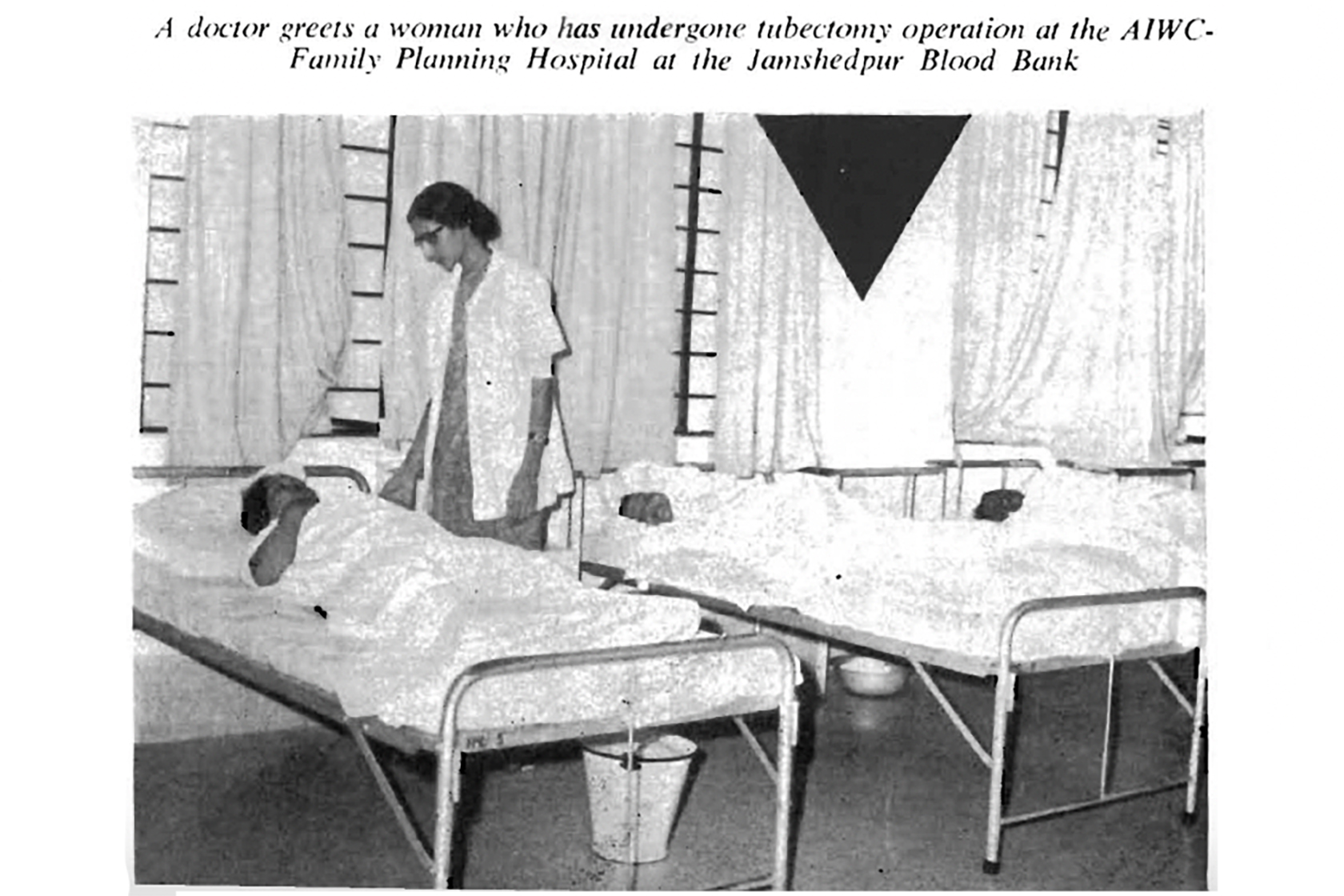 A black-and-white photograph from 1976 shows a female doctor leaning over the bed of a patient recovering from surgery. The image caption reads: “A doctor greets a woman who has undergone tubectomy operation at the AIWC-Family Planning Hospital at the Jamshedpur Blood Bank.”