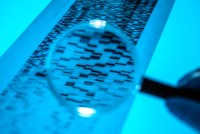 A photo of a magnifying glass held up to a printed genome sequence.