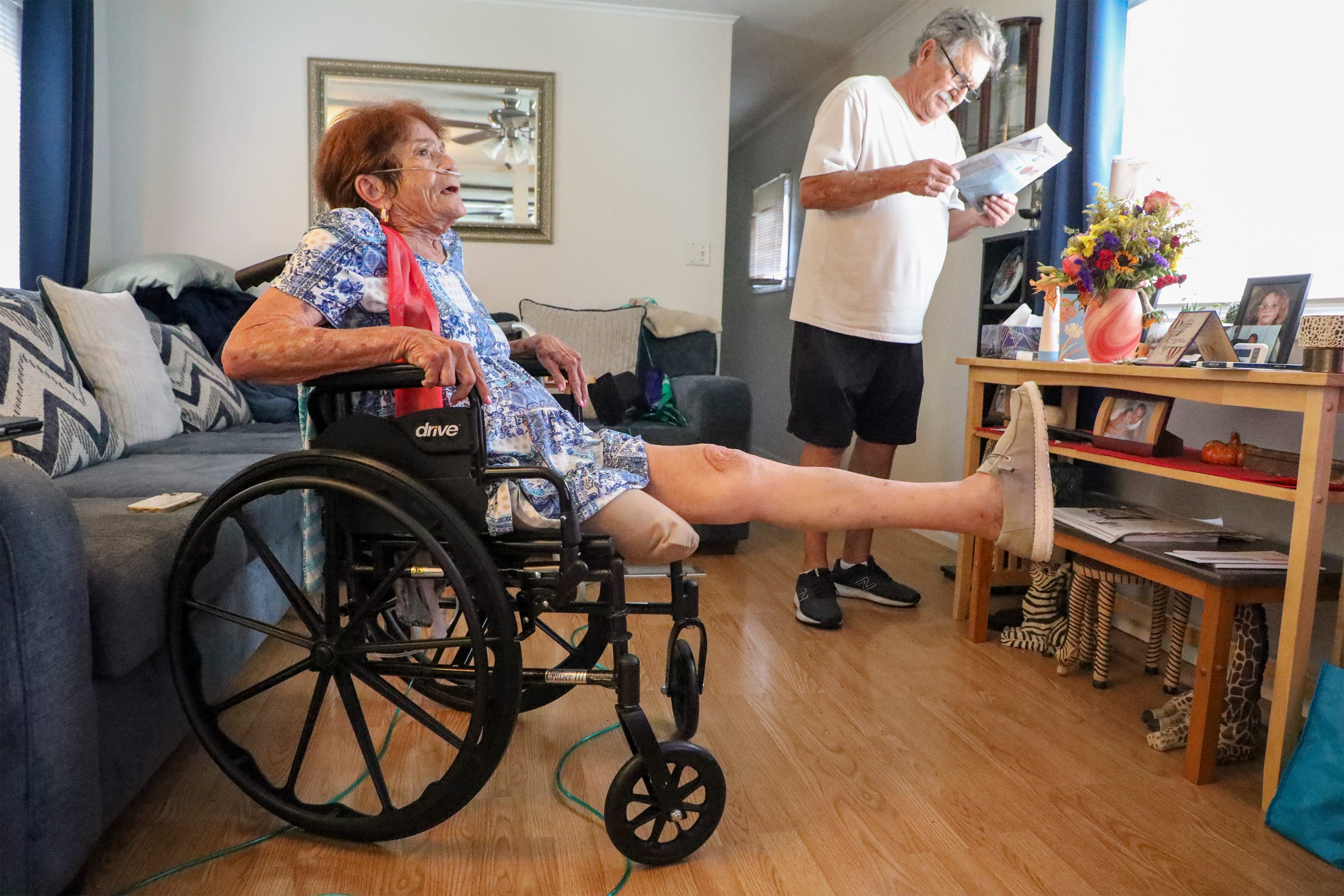 A photo of a woman stretching her left leg while sitting in a wheelchair.