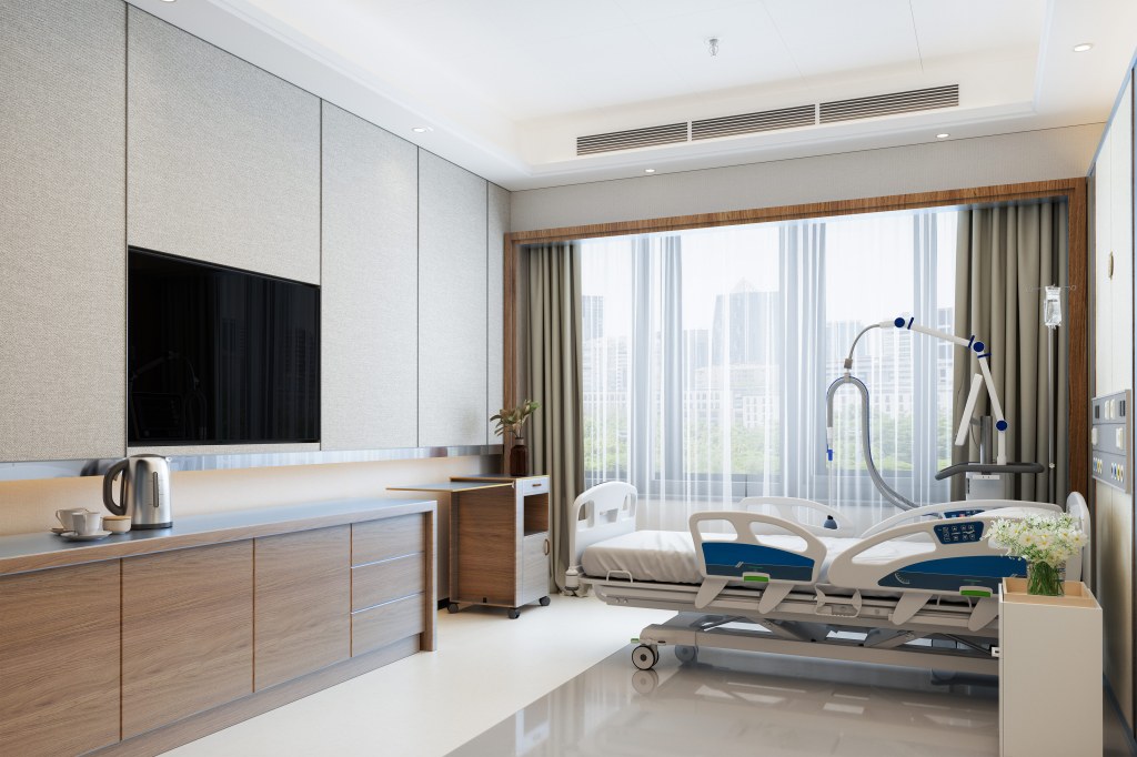 A photo of the interior of a luxury hotel room. The room features a flat screen TV, an electric kettle, and a bouquet of flowers.