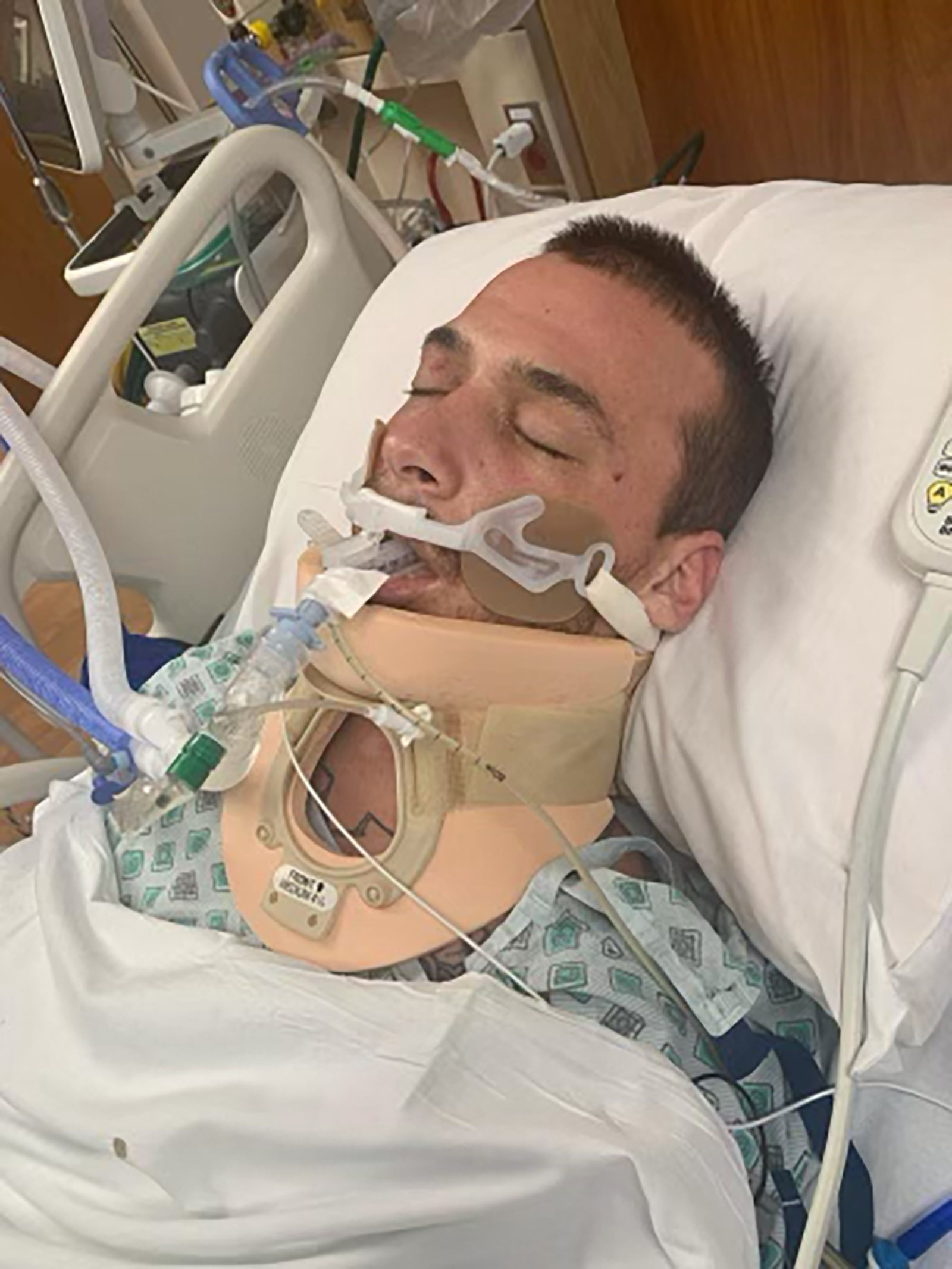 الکساندر ریوس بیهوش روی تخت بیمارستان دراز کشیده است.  او با دستگاه تنفس مصنوعی تحت درمان است و به گردن بند مجهز شده است.