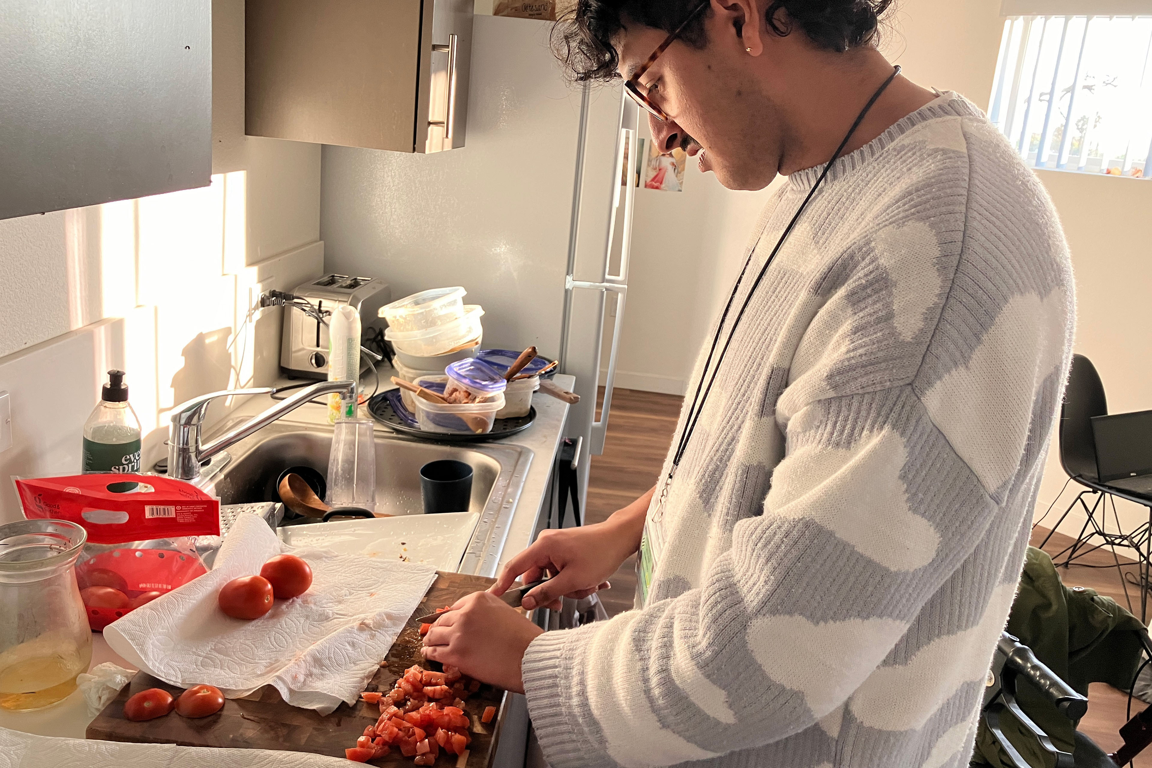 Julian Prado cuts tomatoes in Carla Brown's kitchen.