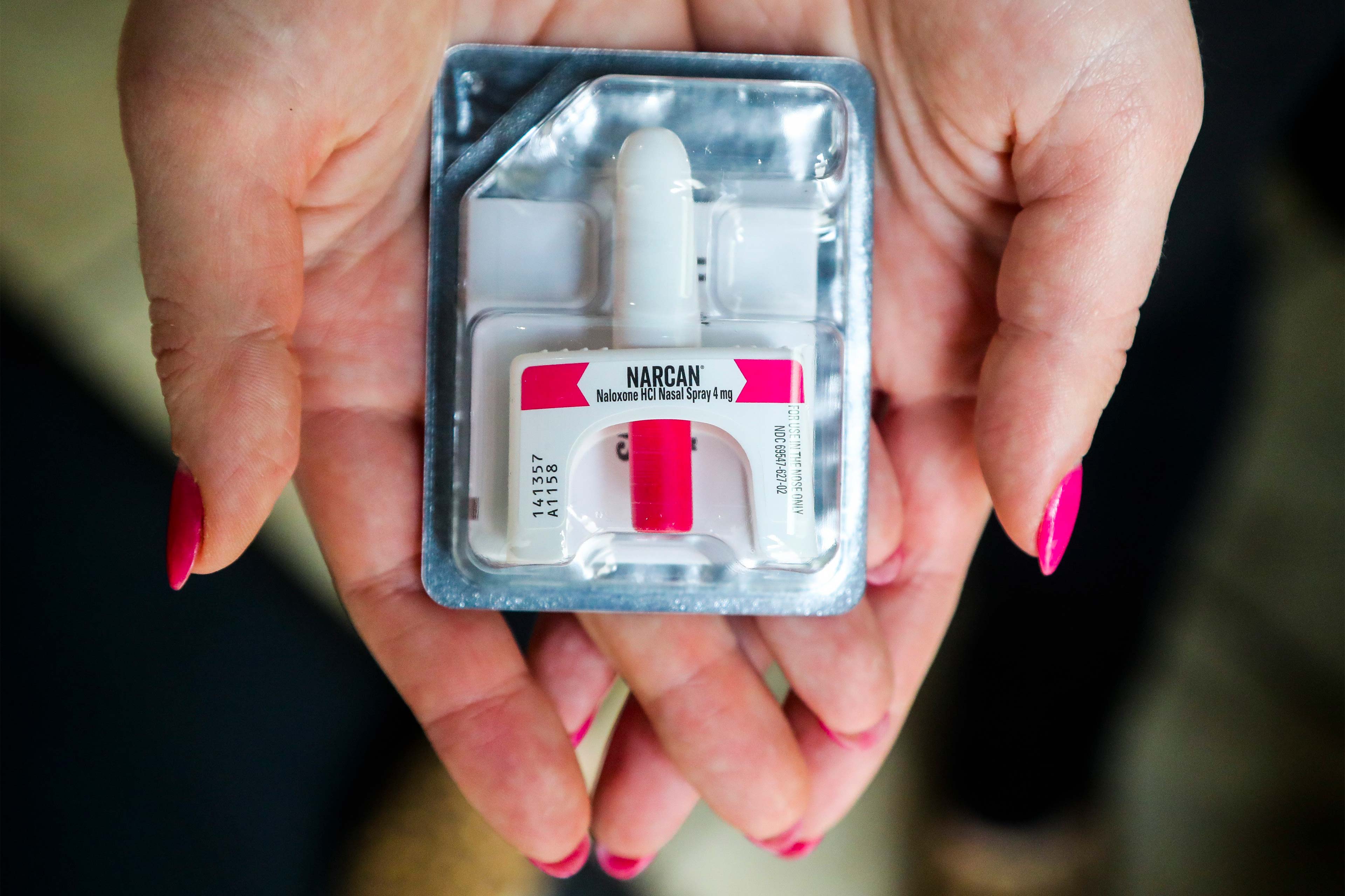 A photo of a woman's hands holding a package of Narcan.