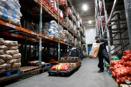A man works in a large warehouse moving bags of produce
